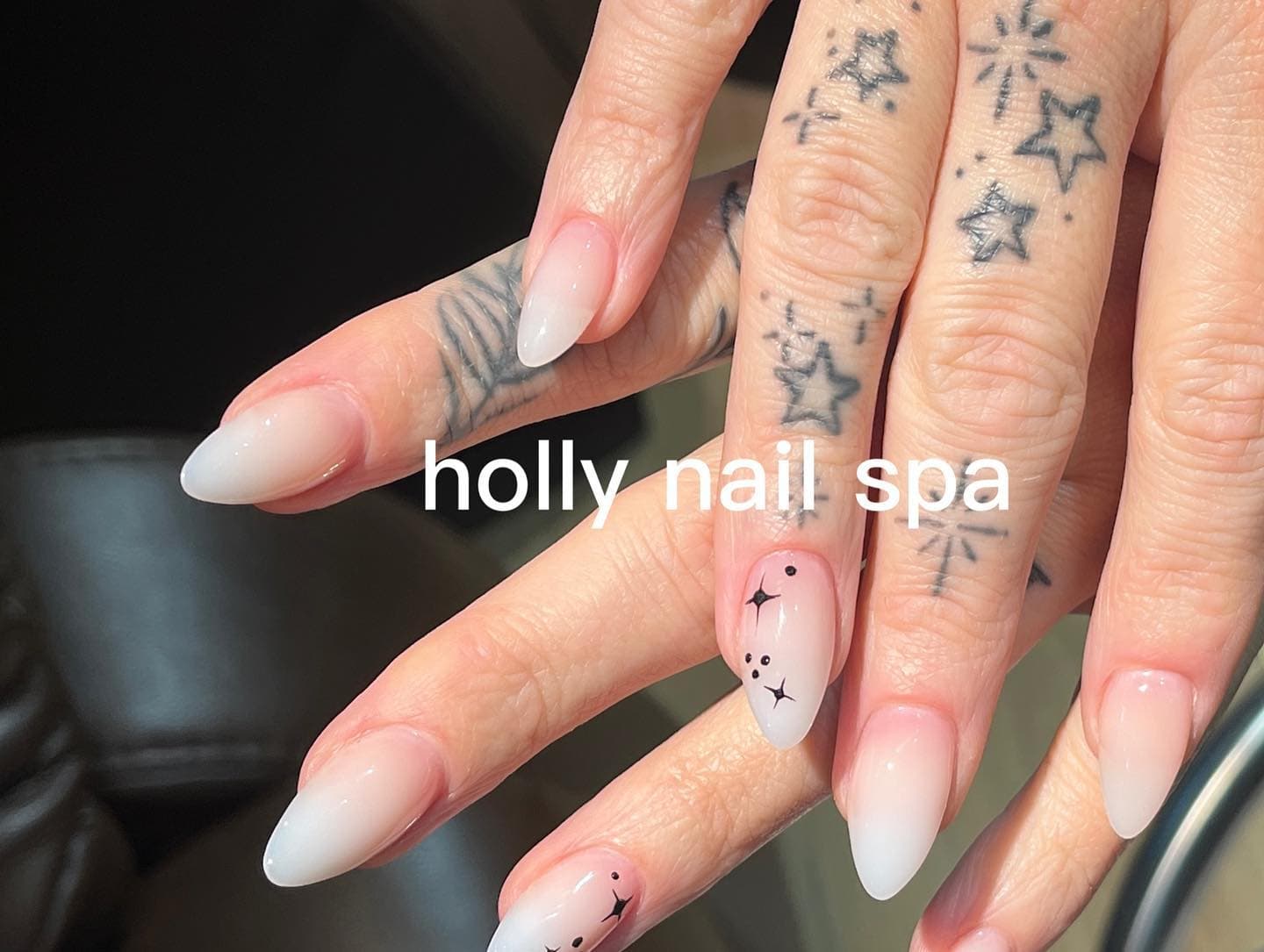 Unghie nude ombré bianco latte con stelle nere dipinte